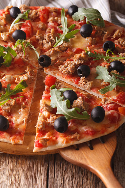 istock Sliced pizza with tuna, olives and arugula close-up. vertical 638864820
