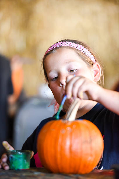 lächelndes kleines mädchen malt einen kürbis - pumpkin child little girls pumpkin patch stock-fotos und bilder