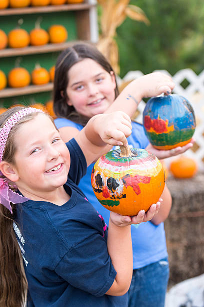 ragazze sorridenti che mostrano le loro zucche dipinte - pumpkin child little girls pumpkin patch foto e immagini stock