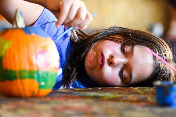 bambina che dipinge una zucca - pumpkin child little girls pumpkin patch foto e immagini stock