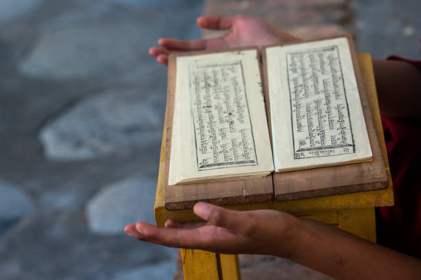 Hands of a Tibetan monk with an buddhist prayer book.