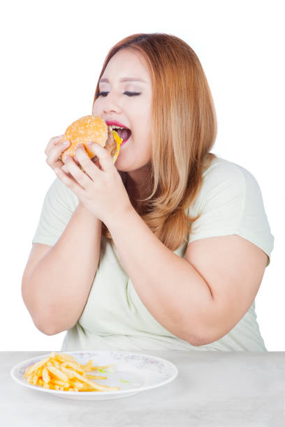 istock Overweight blonde woman eats burger 638870530