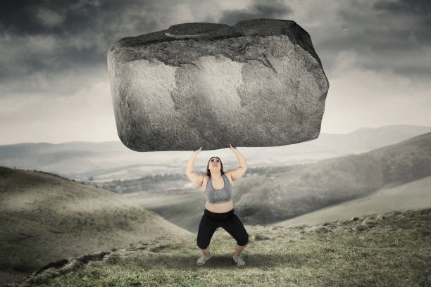 istock Obese woman lifting stone in hills 638872400