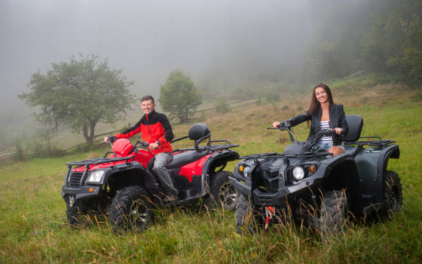 couple heureux au volant d’un vtt à quatre roues tout-terrain - fourwheeler photos et images de collection