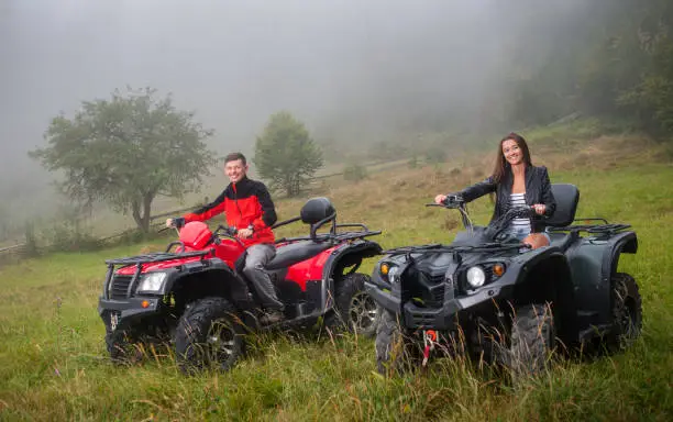 Photo of Happy couple driving four-wheeler ATV offroad