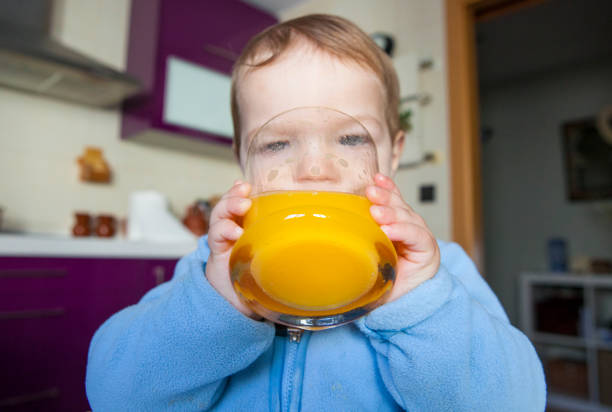 istock Baby boy drinking orange fresh juice 638875322