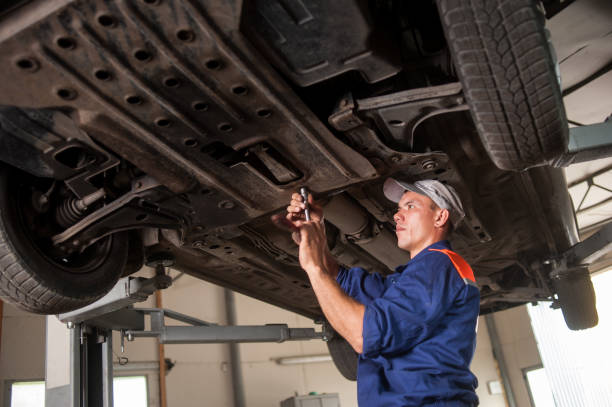 Portrait of car mechanic working with tools under car Car mechanic examining lifted car at repair service station. Using tools mechanic working under car stock pictures, royalty-free photos & images