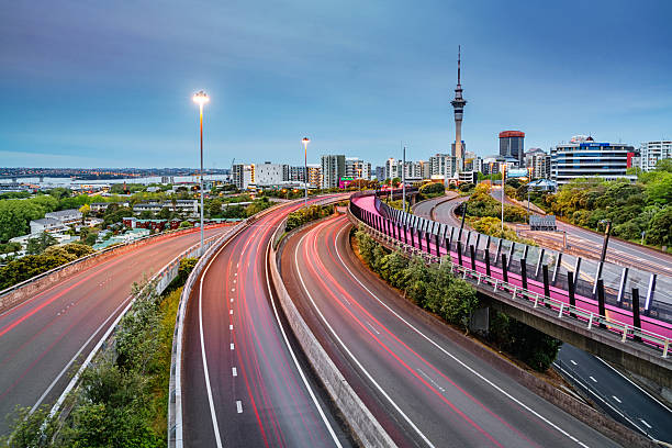 Auckland Light Path Bicycle Lane Highway Traffic New Zealand Auckland Sky Tower and motion blurred highway traffic lights during twilight. Illuminated Light Path Bicycle Lane beside the Highway. Auckland City, New Zealand. auckland stock pictures, royalty-free photos & images