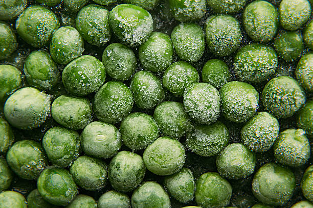 Fresh frozen green peas with hoarfrost closeup as background.