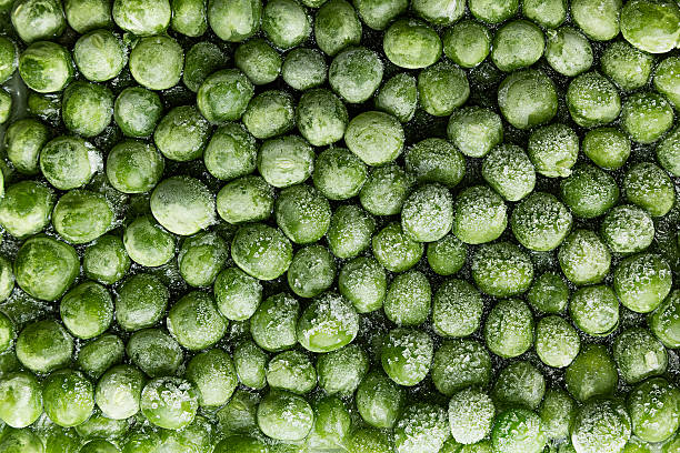 Fresh frozen green peas with hoarfrost closeup as background.