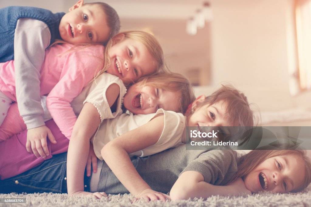 Children having fun at home. Large group of children lying at floor and having fun. Looking at camera. Community Stock Photo