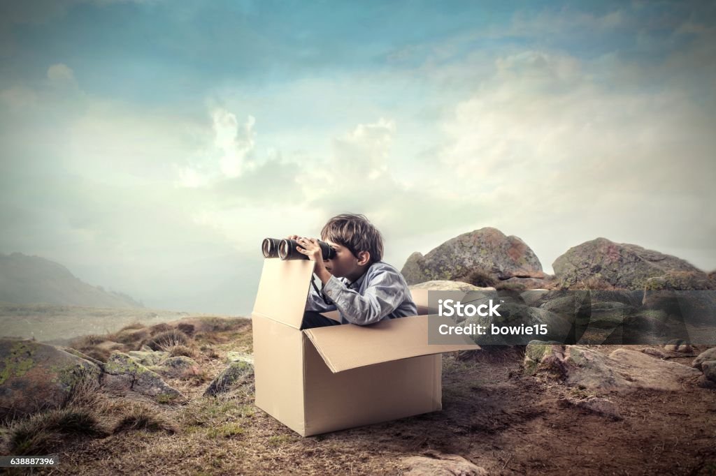 Little boy with an obstacle Little boy sitting alone in a paper box and looking away with an obstacle Child Stock Photo