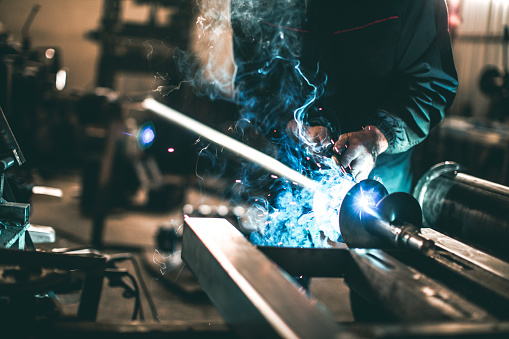 Welder welding metal in workshop with sparks