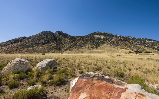 Cody, Wyoming, USA. The arid landscape of the prairie in late summer with view of foothills of Rocky Mountains with an isolated ranch house on a bright day near Cody, Wyoming, USA.