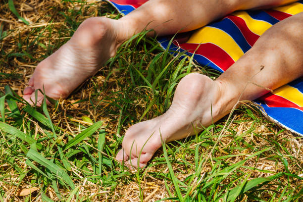 gambe di donna sdraiate su un panno colorato nell'erba - podiatry human foot grass barefoot foto e immagini stock