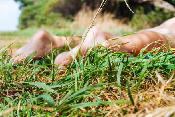 gambe di donna sdraiate su un panno colorato nell'erba - podiatry human foot grass barefoot foto e immagini stock