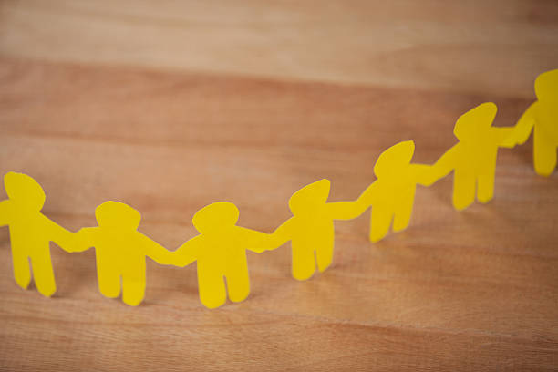 istock Paper cut outs forming a human chain on wooden table 638900920