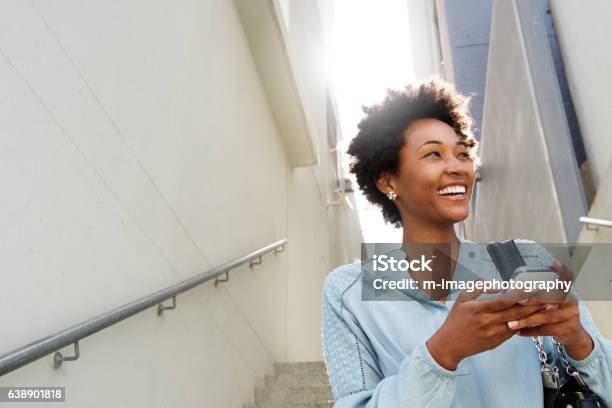 Young black woman on steps with mobile phone