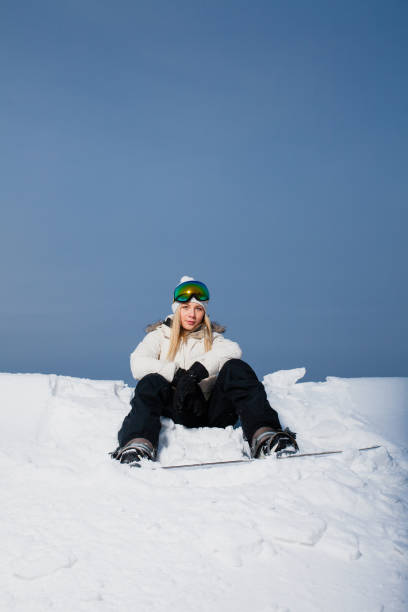 istock Young woman sitting on snow-covered mountainside with her snowboard 638903736