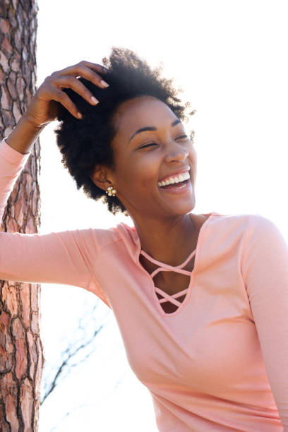 istock Cheerful young black woman leaning on tree trunk 638905948