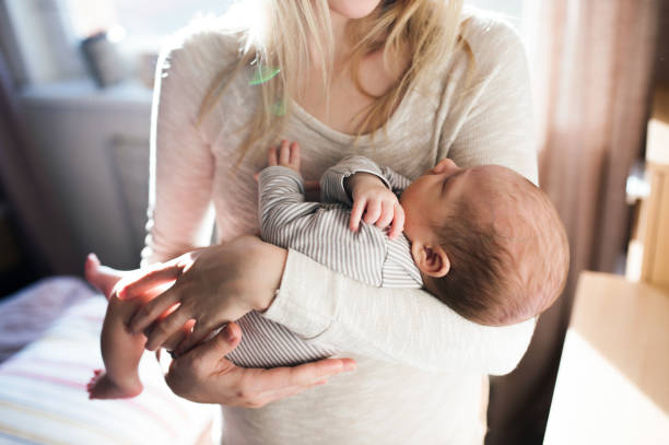 unkenntlich stirnende junge mutter hält baby sohn in den armen - tranquil scene sleeping clothing expressing positivity stock-fotos und bilder