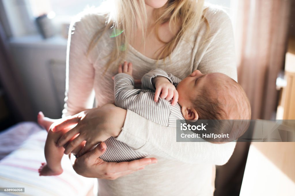 Unrecognizable young mother holding baby son in her arms Unrecognizable young mother holding her baby son in her arms Baby - Human Age Stock Photo