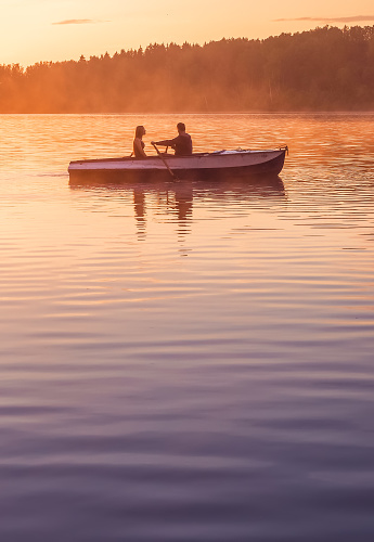 A beautiful golden sunset on the river. Lovers ride in a boat on a lake during a beautiful sunset. Happy couple woman and man together relaxing on the water. The beautiful nature around. Russia Ruza ReservoirA beautiful golden sunset on the river. Lovers ride in a boat on a lake during a beautiful sunset. Happy couple woman and man together relaxing on the water. The beautiful nature around. Russia Ruza Reservoir