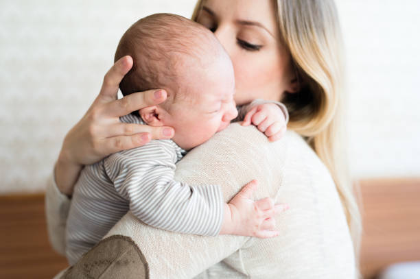 belle jeune mère tenant son petit fils dans ses bras - pleurer photos et images de collection