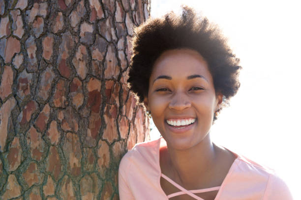 Beautiful young african woman leaning on tree