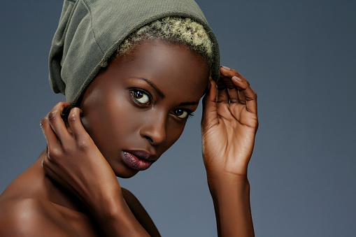 Beauty, fashion portrait. Original looks. Beautiful, lovely  and sensual young african girl.  Attractive African ethnicity,  slim women.   Gray wall background.