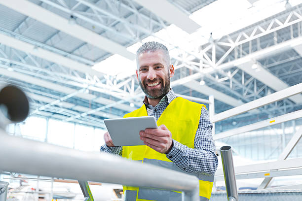 ingeniero aeronáutico que utiliza una tableta digital en un hangar - manual worker fotografías e imágenes de stock