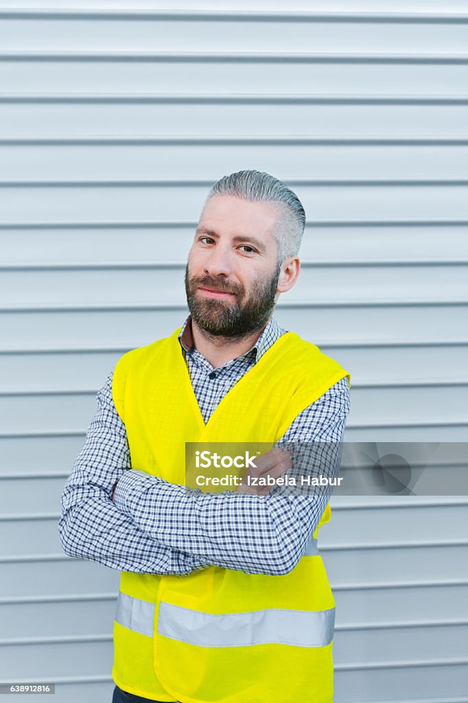 Smiling engineer in front of metal door Engineer standing outdoors in front of metal door, smiling at camera. Adult Stock Photo