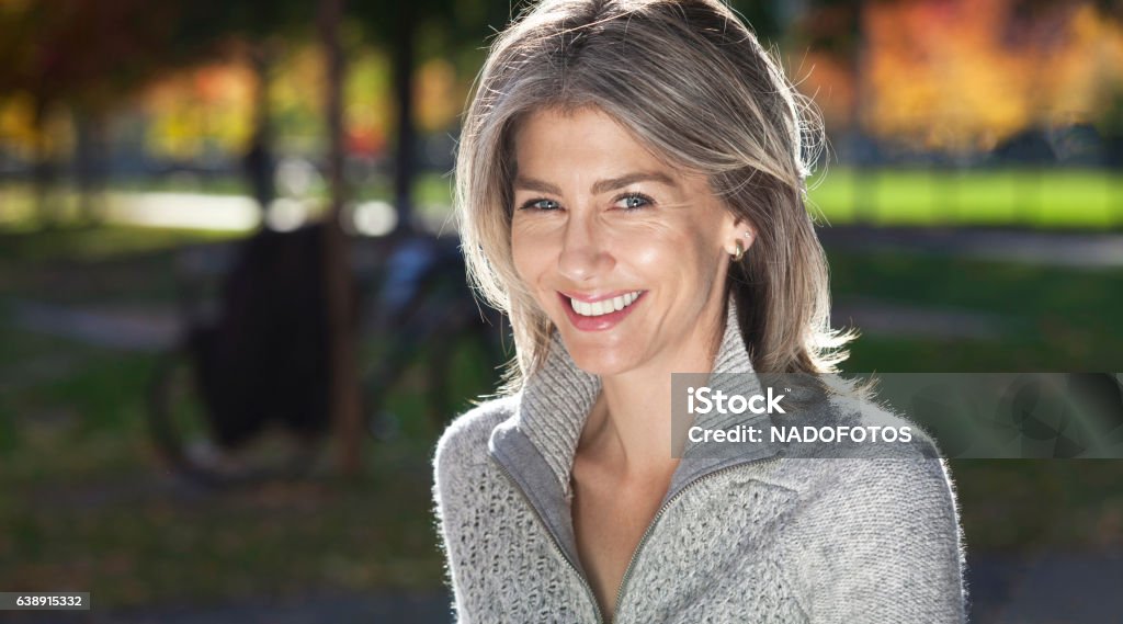 Retrato de uma mulher madura sorrindo para a câmera. fora. - Foto de stock de Mulheres royalty-free