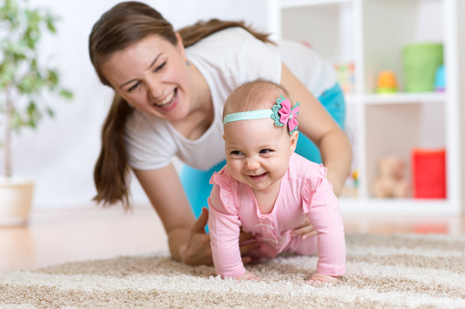 Funny crawling baby girl with mother at home