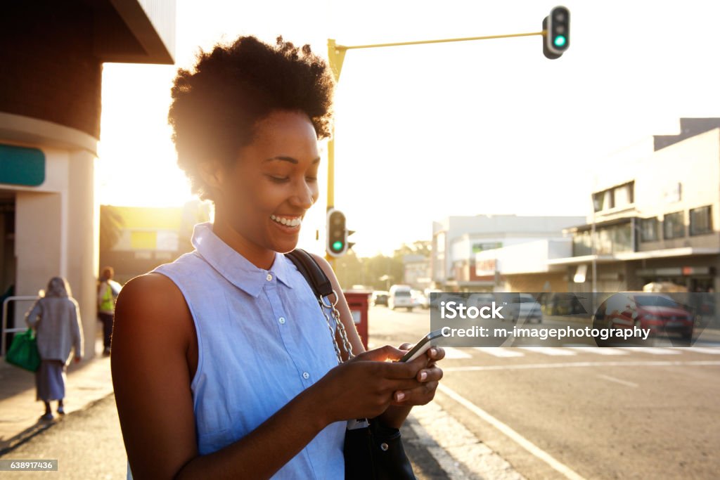 Beautiful african woman using cellphone outdoors Close up portrait of beautiful young african woman using cellphone outdoors in the city Women Stock Photo