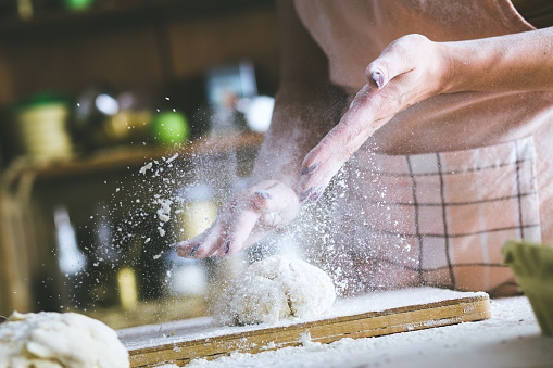 Close up of female baker hands kneading dough