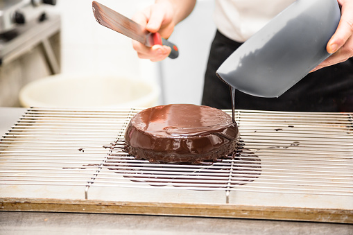 Pastry Chef pouring chocolate on cake