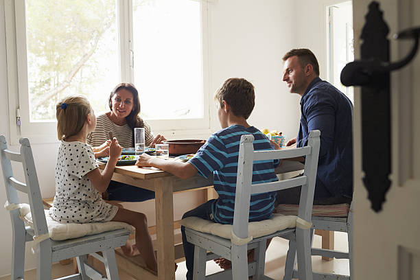 famiglia a casa nel mangiare insieme - family dinner eating meal foto e immagini stock