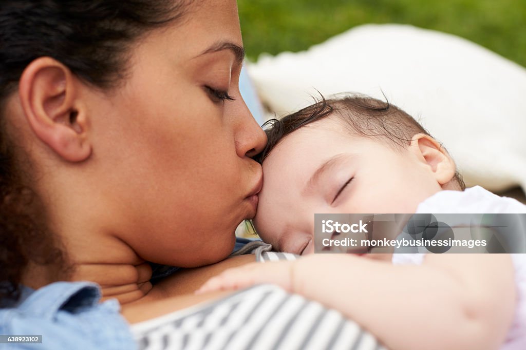 Close Up Of Mother With Baby Relaxing On Rug In Garden Baby - Human Age Stock Photo