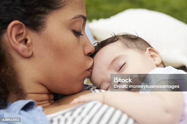 Close Up Of Mother With Baby Relaxing On Rug In Garden Stock Photo - Download Image Now