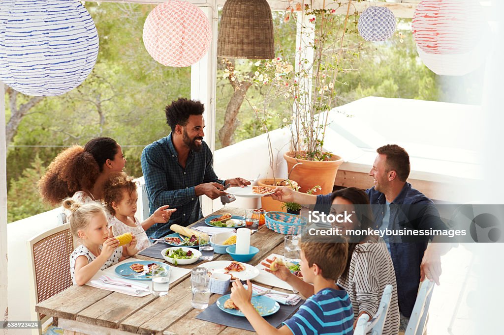 Famílias desfrutando de refeições ao ar livre no terraço juntas - Foto de stock de Família royalty-free