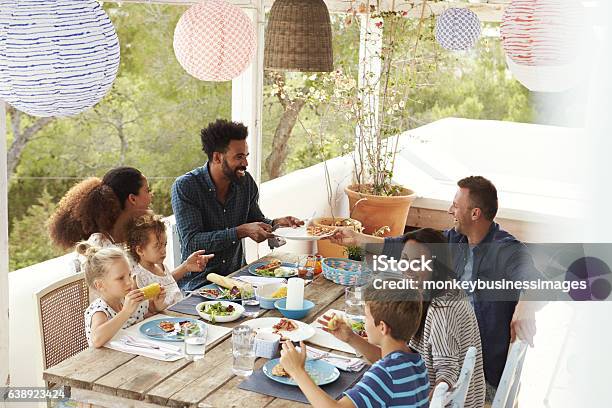 Foto de Famílias Desfrutando De Refeições Ao Ar Livre No Terraço Juntas e mais fotos de stock de Família