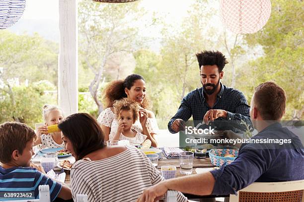Families Enjoying Outdoor Meal On Terrace Together Stock Photo - Download Image Now - Family, Dinner, Outdoors