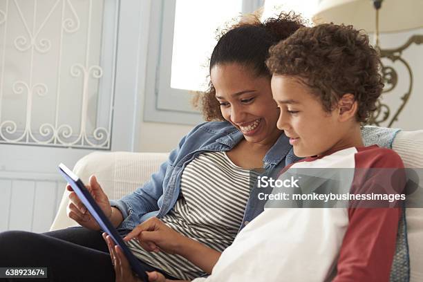 Mother And Son Sitting On Sofa Using Digital Tablet Stock Photo - Download Image Now