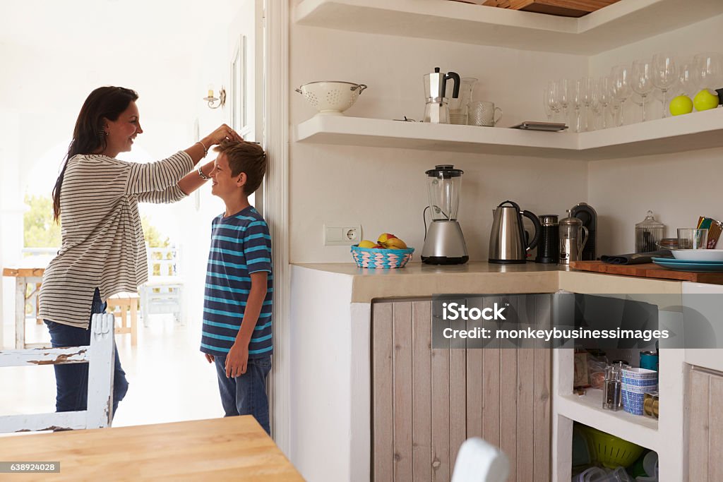 Mother Measuring Son's Height Against Wall Child Stock Photo