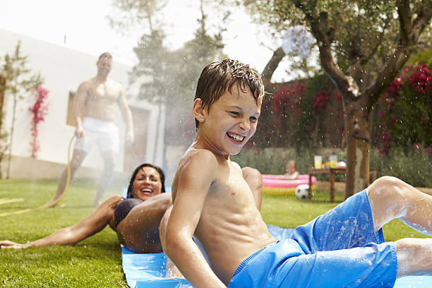 istock Family Having Fun On Water Slide In Garden 638924164