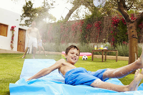 istock Father And Son Having Fun On Water Slide In Garden 638924204