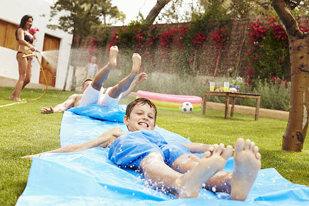 istock Family Having Fun On Water Slide In Garden 638924252