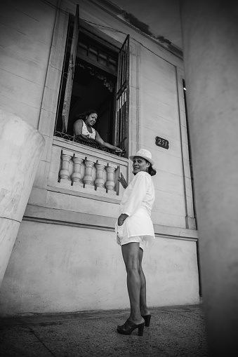 Havana, Cuba - October 8, 2016: Two mature women having a break  on the street corner and talking at Malecon in Havana, Cuba. This is a famous downtown shore line, lined up with great architecture from past now mostly run down after years being exposed to elements from Caribbean sea. Popular place for people of Havana to hang around, be in love, play music and fish. A must see location when visiting this great city. 