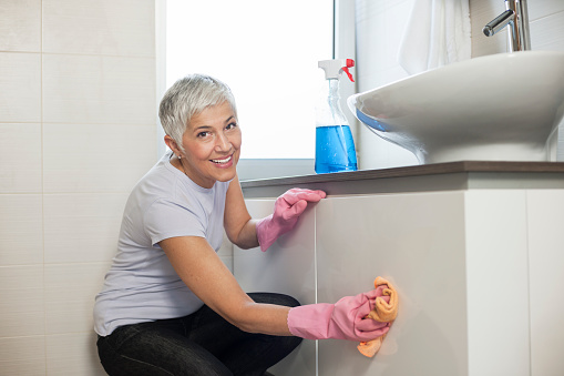 Mature woman cleaning home, washing bathroom
